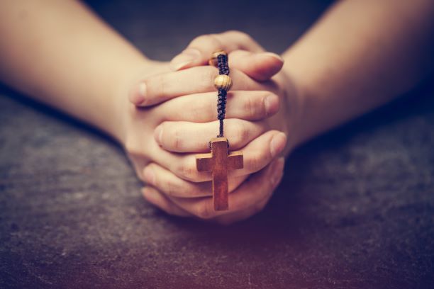 woman praying with a rosary maly